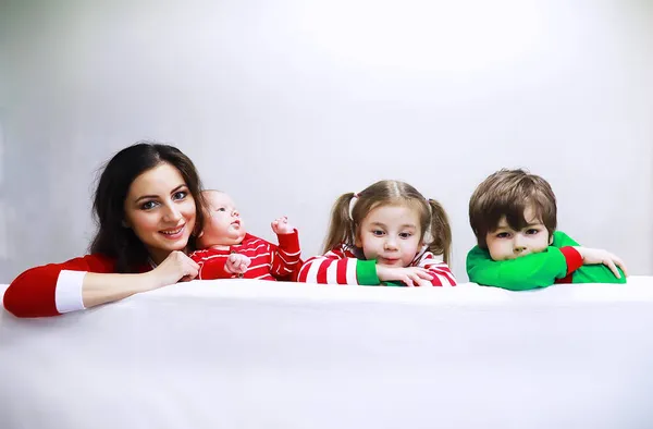 一个穿着条纹睡衣的家庭正在家中休息 打扮成精灵的小孩躺在沙发上 有旗帜的快乐家庭 — 图库照片
