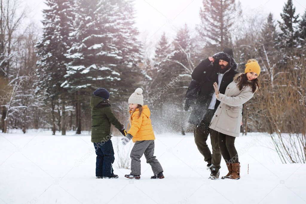 Happy family playing and laughing in winter outdoors in snow. City park winter day.