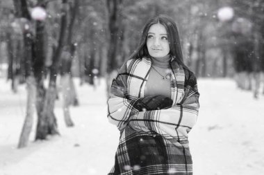 Kışın bulutlu bir günde, karla kaplı tarlalarda ve ormanlarda bir kız.