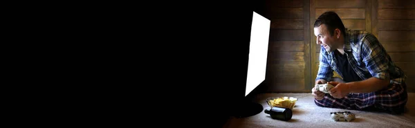 大きなテレビ画面の前のジョイスティックのコンソールで遊ぶギャンブルの男とテキスト用の長い黒いバナー — ストック写真