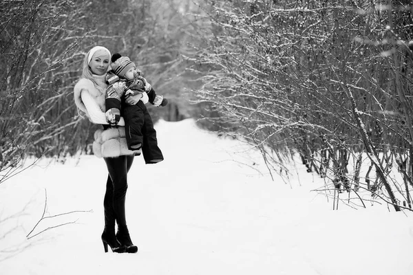若い母親は冬の日に歩く彼女の腕の中で赤ちゃんとパー — ストック写真