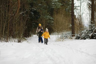Mutlu bir aile kışın dışarıda karda oynar ve güler. Şehir parkı kış günü.