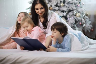 Çocuklu bir aile Noel tatilinde yorganın altında eğleniyor..
