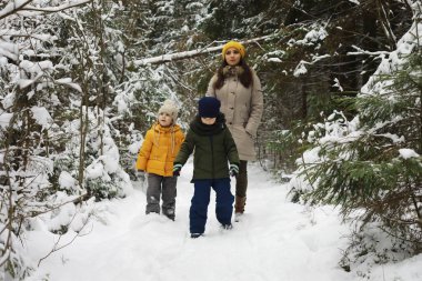 Mutlu bir aile kışın dışarıda karda oynar ve güler. Şehir parkı kış günü.