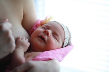 Yeni doğmuş bir bebek annesinin kollarında yatıyor. Avrupa görünümlü güzel bebek uyuyor.