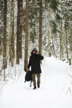 Kış ormanlarında sakallı adam. Çekici, mutlu, sakallı genç bir adam parkta yürüyor..