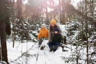 Mutlu bir aile kışın dışarıda karda oynar ve güler. Şehir parkı kış günü.