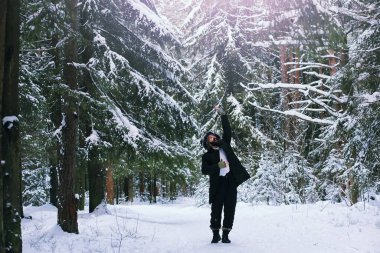 Kış ormanlarında sakallı adam. Çekici, mutlu, sakallı genç bir adam parkta yürüyor..
