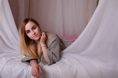 Sarı saçlı ve gri kazaklı kız.