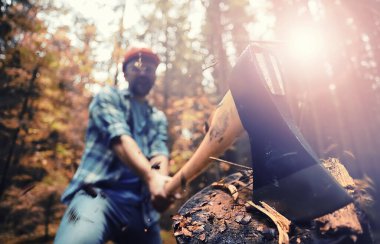 Ormanda ağaç kesen baltalı bir erkek işçi..