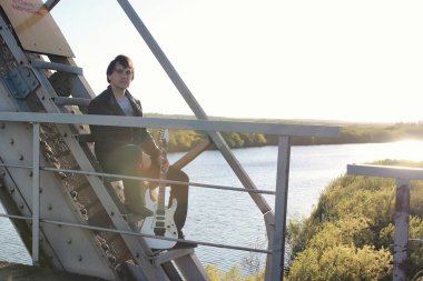 bir adam açık havada ve endüstriyel yatay olarak bir elektro gitar ile