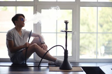 Güneş gözlüğü Asyalı genç adam windo bir nargile sigara