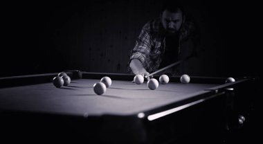 Sakallı bir adam büyük bir bilardo oynar. 3,5 metrelik havuzda parti. Kulüp oyununda erkekler için bilardo. Elinde ıstakayla bir adam piramidi kırar.