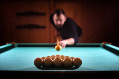 Sakallı bir adam büyük bir bilardo oynar. 3,5 metrelik havuzda parti. Kulüp oyununda erkekler için bilardo. Elinde ıstakayla bir adam piramidi kırar.