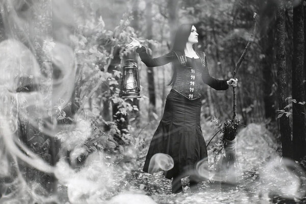 A woman in a witch suit in a dense forest on a ritual