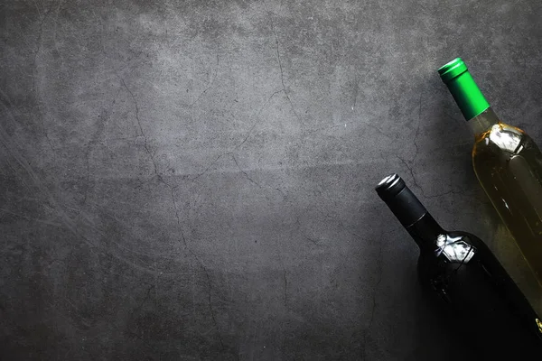 Masada bir bardak kırmızı şarap. Siyah şişe ve bir bardak şarap..