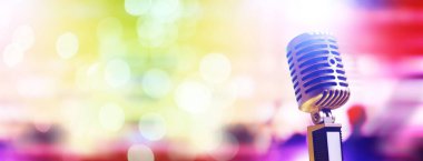 Arka planda arka ışıklandırmalı Retro tarzı mikrofon. Ses, müzik ve karaoke için klasik gümüş mikrofon. Konuşma yayın ekipmanı. Canlı pop, rock müzik performansı. Seçici odak