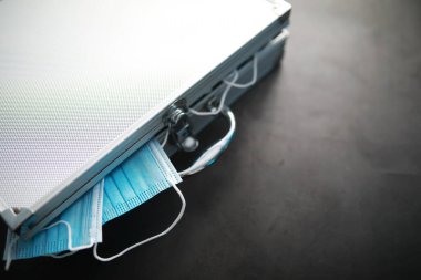 Tek kullanımlık maskelerle dolu metal bir bavul. Yeni gerçeklik, yeni değerler. Para maskeleri.