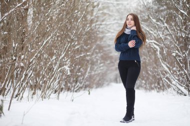 Kış parkında yürüyüş yapan genç bir kız. Kış ormanlarında Noel tatili. Kız parkta kışın tadını çıkarıyor.