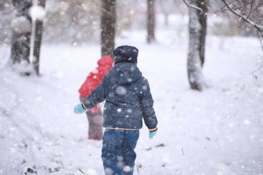Çocuklar parkta ilk karla yürür. 