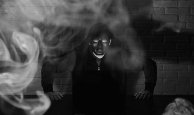 Siyah maskeli ve başlıklı bilgisayar korsanı Monito 'nun önündeki masada.