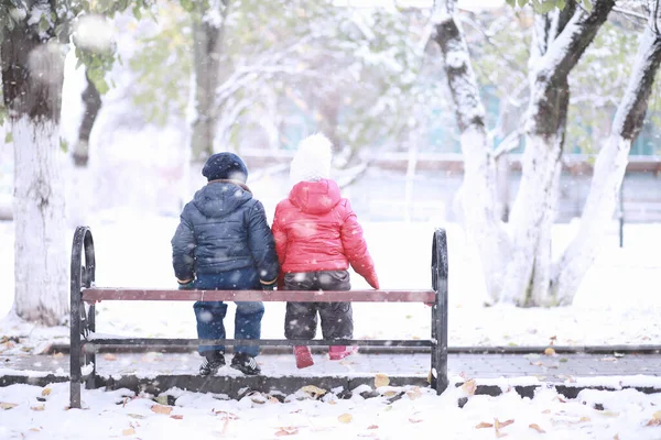 Çocuklar parkta ilk karla yürür. 