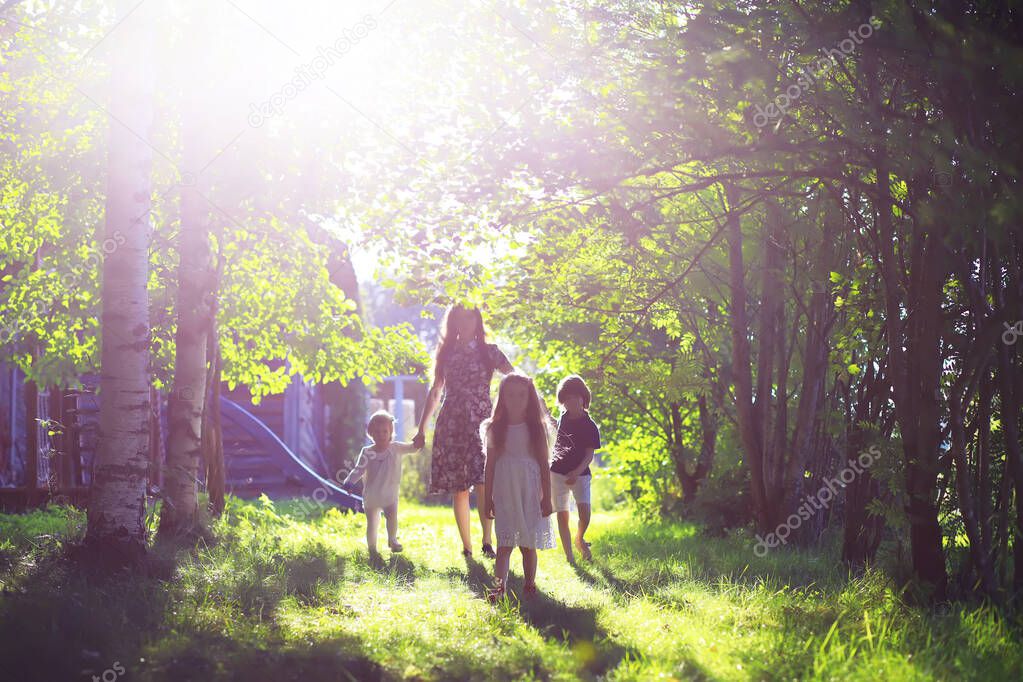 Young large family on a summer morning walk. Beautiful mother with children playing in the park.