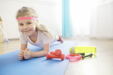 Spor ve sağlıklı bir yaşam tarzı. Çocuk evde spor yapıyor. Yoga paspası ve halat atlama. Ev egzersizleri kavramına sahip spor geçmişi.