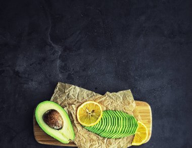 Avokado yemek tarifleri. Tahta kesme tahtasında servis edilen olgun yeşil avokado..