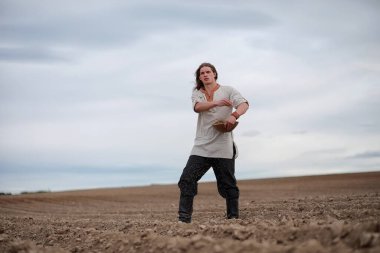 İskandinav görünüşlü genç bir köylü grai ile alan ekiyor