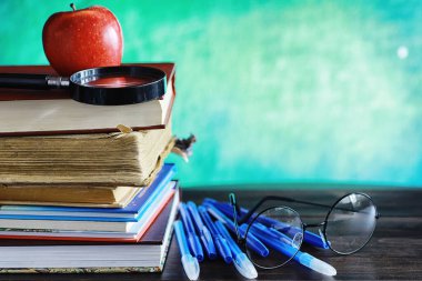 Eğitim konsepti. Bir yığın ders kitabı ve masanın üstünde gözlüklü ve bilgisayarlı bir kitap. Okul kahvaltısı elma ve ev ödevi.