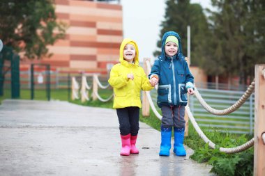 İki küçük çocuk, erkek ve kız, soğuk bir sonbahar gününde hayvanat bahçesinde maymun gösterisi izliyorlar. Çocuklar safari parkında hayvanları izliyor.