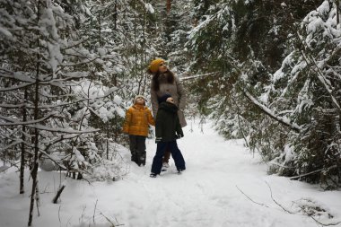 Mutlu bir aile kışın dışarıda karda oynar ve güler. Şehir parkı kış günü.