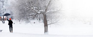 Şemsiyeli bir kış yürüyüşü. Şemsiyeli bir adam, kış manzarasının arka planında yürür, kış manzarası