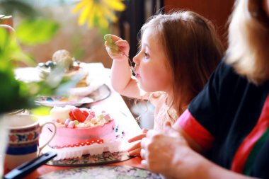 Çocuklar doğum gününü evde pasta ve balonlarla kutluyor.