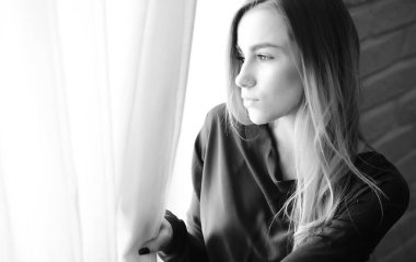 Genç bir kız büyük bir dairede dinleniyor.