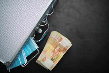 Tek kullanımlık maskelerle dolu metal bir bavul. Yeni gerçeklik, yeni değerler. Para maskeleri.