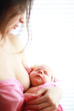 Yeni doğmuş bir bebek annesinin kollarında yatıyor. Avrupa görünümlü güzel bebek uyuyor.