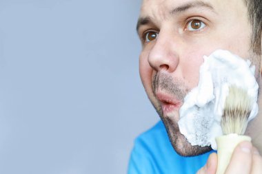 Bir adam aynanın önünde tıraş olur. Tıraş köpüğü. Tek kullanımlık jilet..