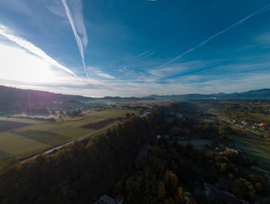 Slovenya 'nın Trzic bölgesinin sabah hava aracı panoraması. Görünür sabah sisi, katmanlı puslu sis ve güneş doğmak üzere..