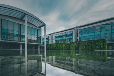 Reykjavik belediye binası bulutlu bir yaz gününde suya alçak bir perspektiften ve yansımadan baktı.