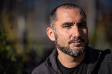 Güneşli bir günde şehir ortamında bir yerlerde oturan modern bir gencin portresi..