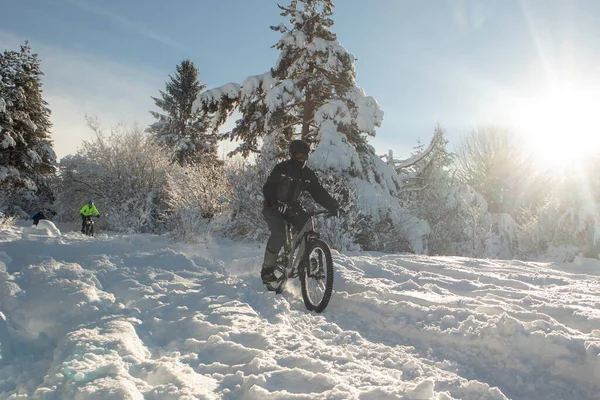 Snowy descent with a mountain bike. Snow downhill with bike, mtb action in winter, with deep snow and sun as a backlight.