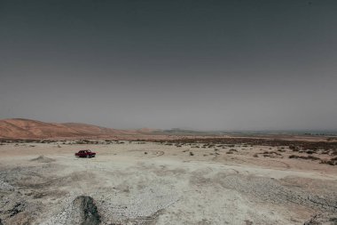 Kırmızı renkli eski bir araba Gobustan doğal park alanına park edilmiş. Yakınlarda taksisi olan Gobustan bölgesinin güzel manzarası..