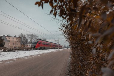 Slovenya 'nın Ljubljana Siska banliyösündeki evlerin önünden kırmızı modern banliyö treni geçiyor. Soğuk kış zamanında Avrupa 'da sabah erkenden banliyö treni.