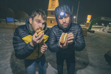 İki tuhaf adam ya da hippi çocuk gece yarısı sosisli sandviç yiyorlar. Sosisli sandviç ile soğuk akşam yemeği..