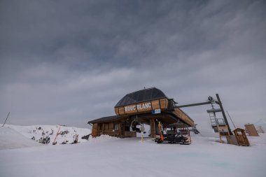 Bulutlu bir kış gününde Meribel - Courchevel kayak alanının üstündeki Bouc Blanc istasyonunun tepesinde. Boş gondol istasyonu.