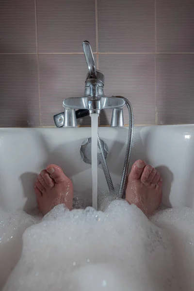 Küvette Köpük Bir Banyodan Sarkan Erkek Ayakları Akıyor Bir Adam — Stok fotoğraf