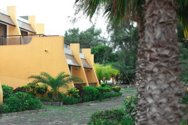 Cabo Verde adalarının başkenti Praia 'daki tipik turistik kompleks ya da otel. Palmiye ağaçlarının arkasında saklanan sarı evler.