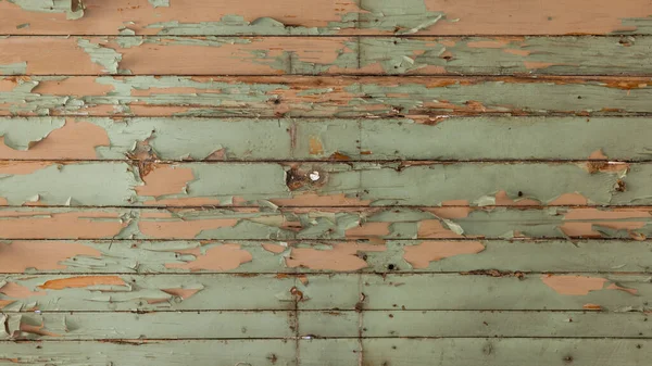 Wooden planks texture, orange and teal light colors on a wall, paint chipping and peeling off.